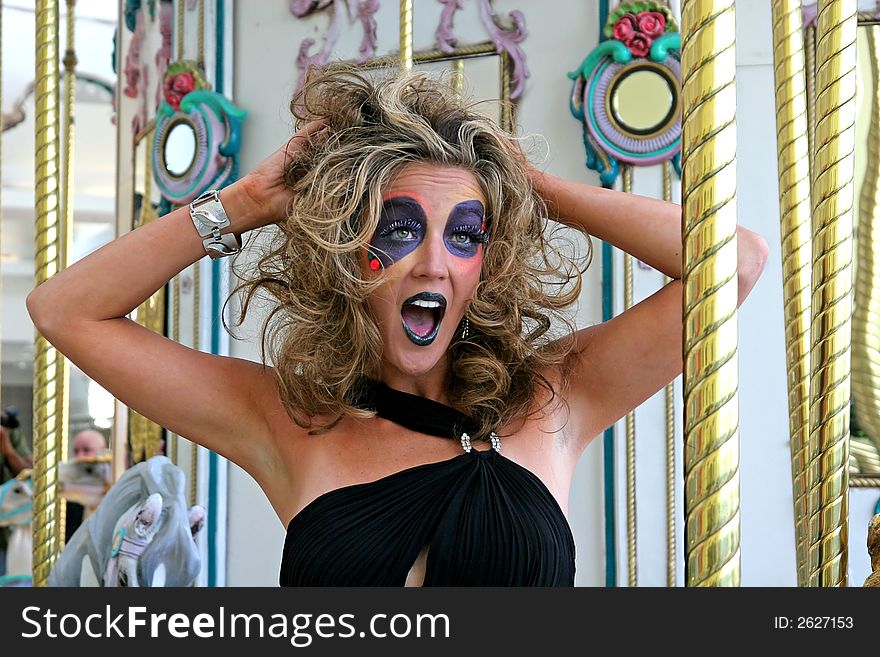 Model with wild makeup on a carousel screaming. Model with wild makeup on a carousel screaming