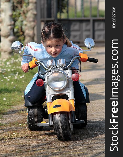 Female child playing with motor-cycle in the garden. Female child playing with motor-cycle in the garden