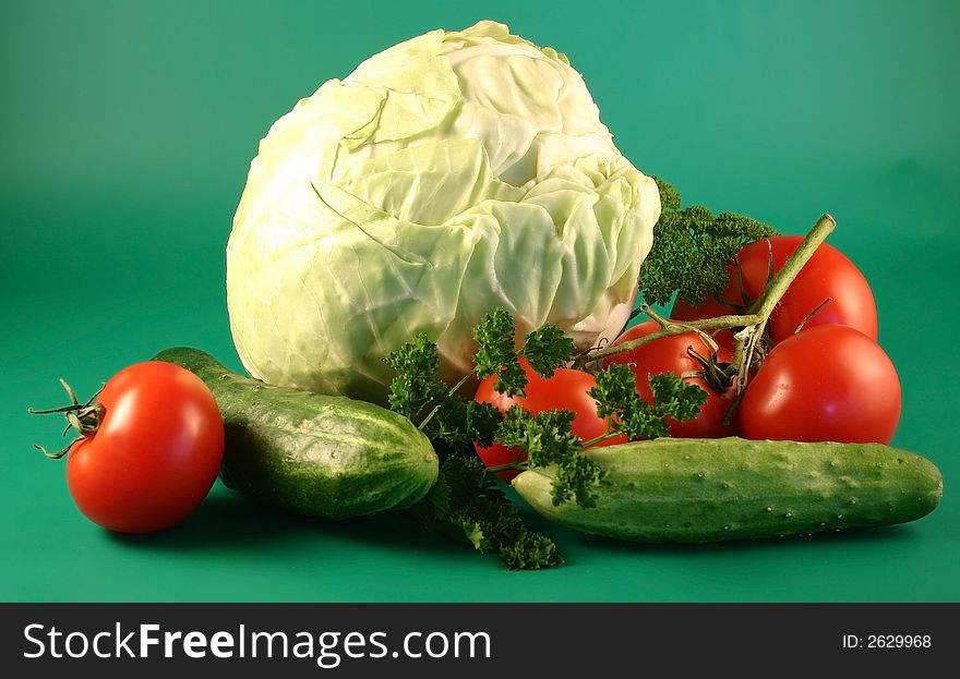 The cabbage, tomatoes and cucumbers are photographed on a green background. The cabbage, tomatoes and cucumbers are photographed on a green background