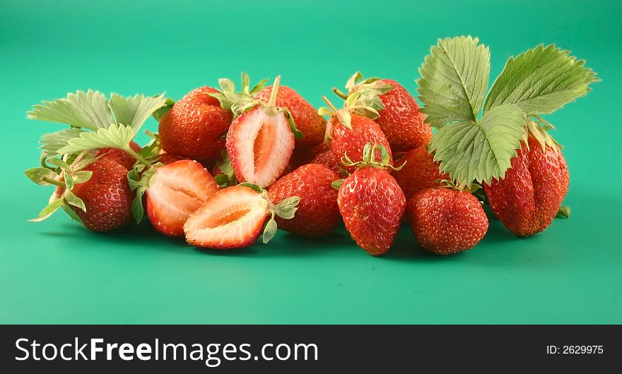 Some strawberries lay on a green background with a leaflet. Some strawberries lay on a green background with a leaflet