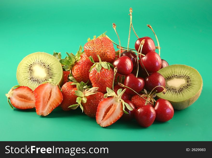 Strawberry and fruit is photographed on a green background