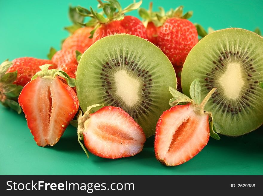 Strawberry and kiwi is photographed on a green background