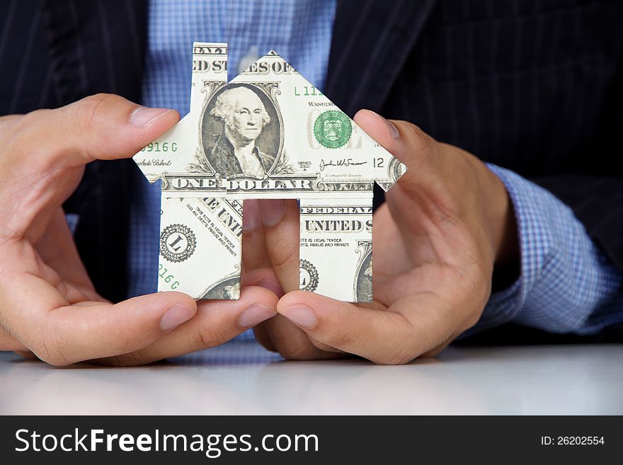 Hand holding banknote house icon, real estate concept.