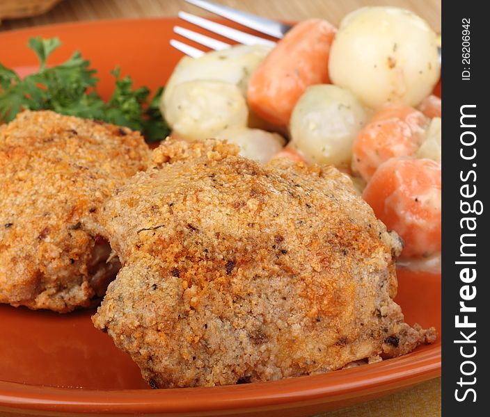 Baked breaded chicken thighs with vegetables on a dinner plate. Baked breaded chicken thighs with vegetables on a dinner plate