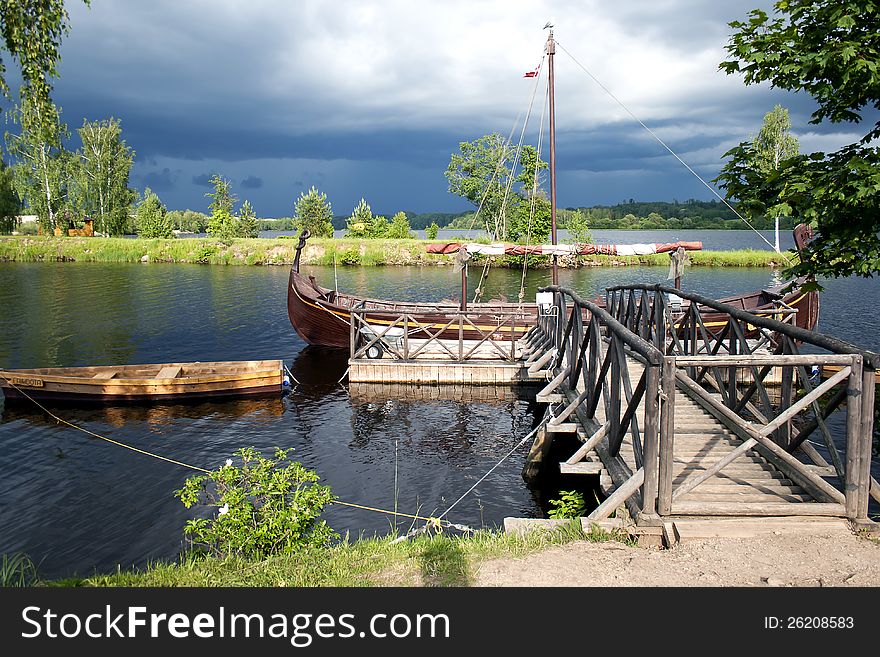 Retro wooden boats near a wooden pier on the river before a thunderstorm. Retro wooden boats near a wooden pier on the river before a thunderstorm