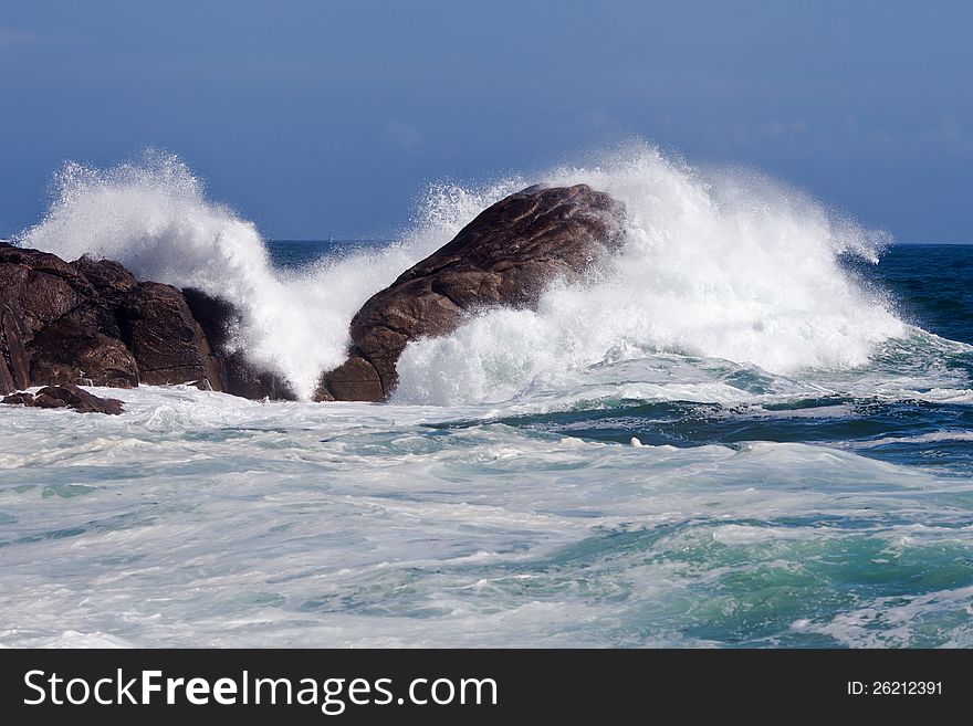 At the rocky coast of Brittany the sea waves crashing against the big rocks and spraying away. At the rocky coast of Brittany the sea waves crashing against the big rocks and spraying away