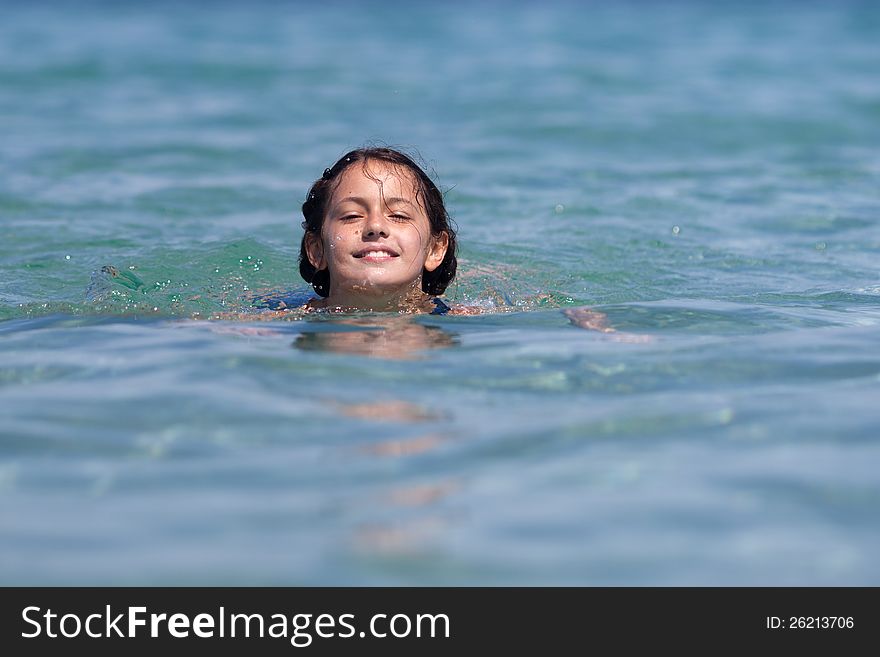 Pretty and smiling girl swims in the sea water