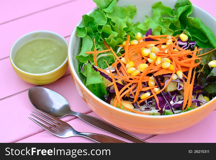 Colorful of vegetables salad with spoon on pink table