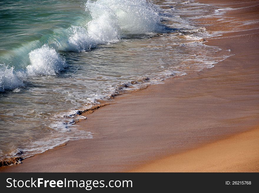 The waves topped with white foam  retreat on the wet sandy beach  as the tide ebbs and flows out twice daily. The waves topped with white foam  retreat on the wet sandy beach  as the tide ebbs and flows out twice daily.