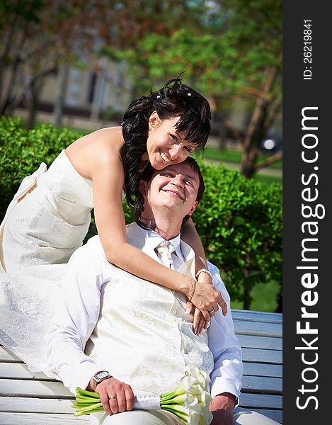 Bride and groom on bench in summer park