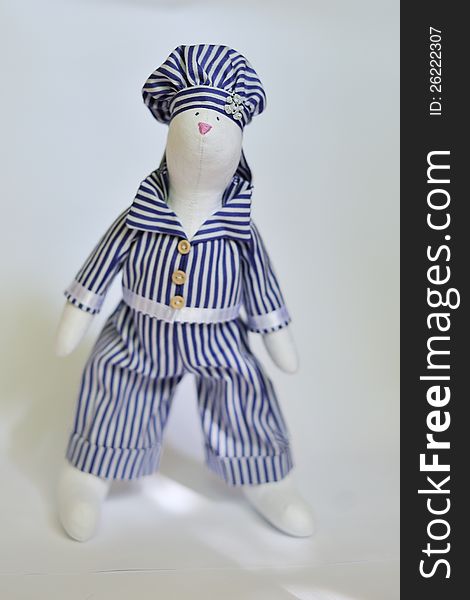 The doll a tilde hare in a striped suit sits. The doll a tilde hare in a striped suit sits