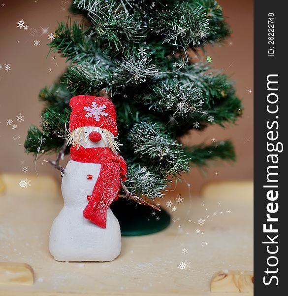 Toy angel a snowman in a red cap under a fir-tree. Toy angel a snowman in a red cap under a fir-tree