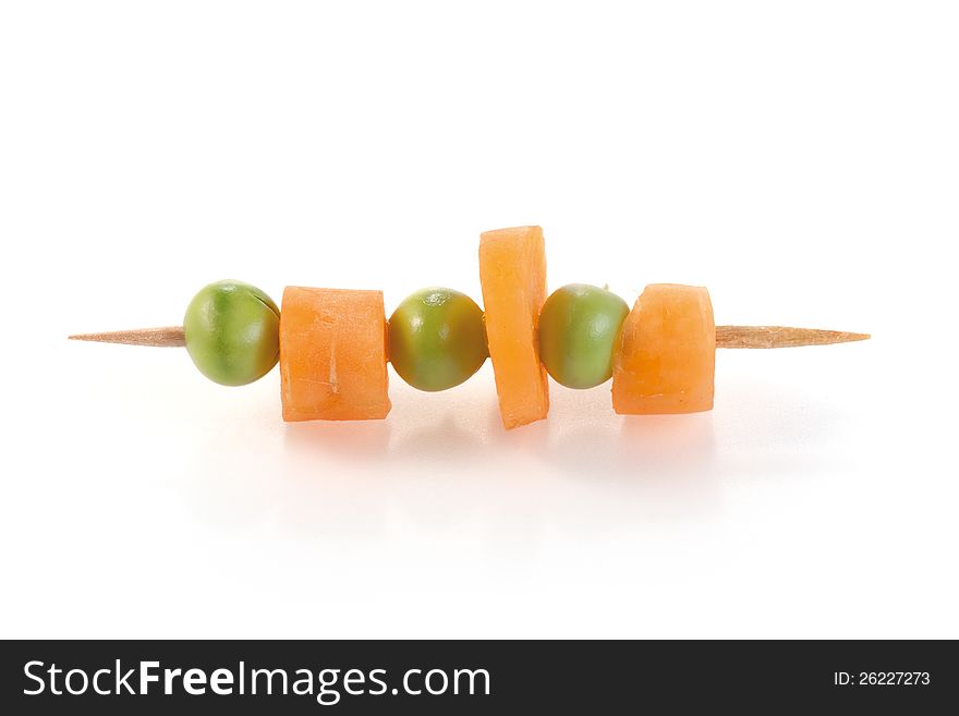 Carrot slices and peas on a skewer. on white background.