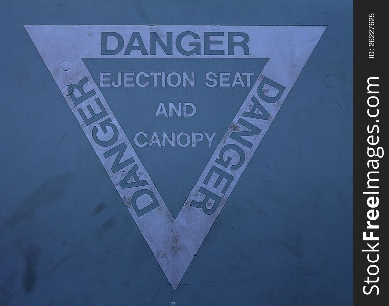 The ejection seat and canopy warning sign near the cockpit of a fighter jet. The ejection seat and canopy warning sign near the cockpit of a fighter jet