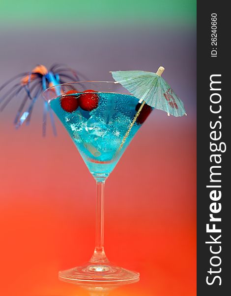 Blue cocktail with ice and umbrella on a colored background