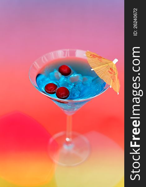 Frash cocktail with ice and umbrella on a colored background