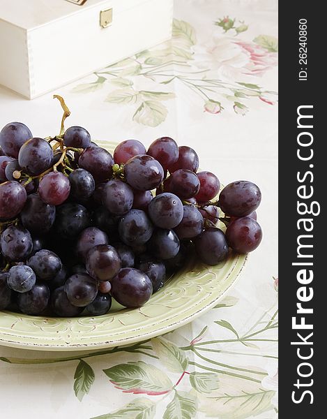 Ripe purple grapes on green rustical plate