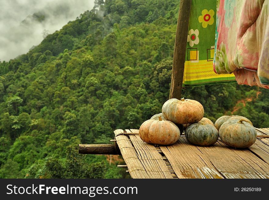 Pumpkin on the bamboo plank in hill tribe's house balcony with mountain background. Pumpkin on the bamboo plank in hill tribe's house balcony with mountain background