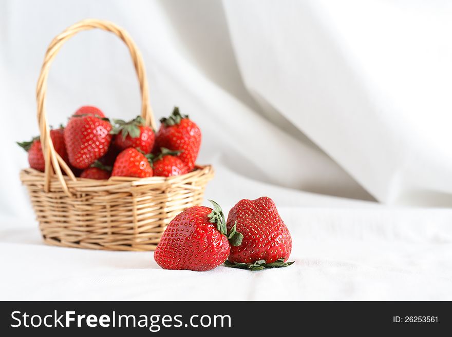 Nice wicker basket full of freshness red strawberry on white cloth background