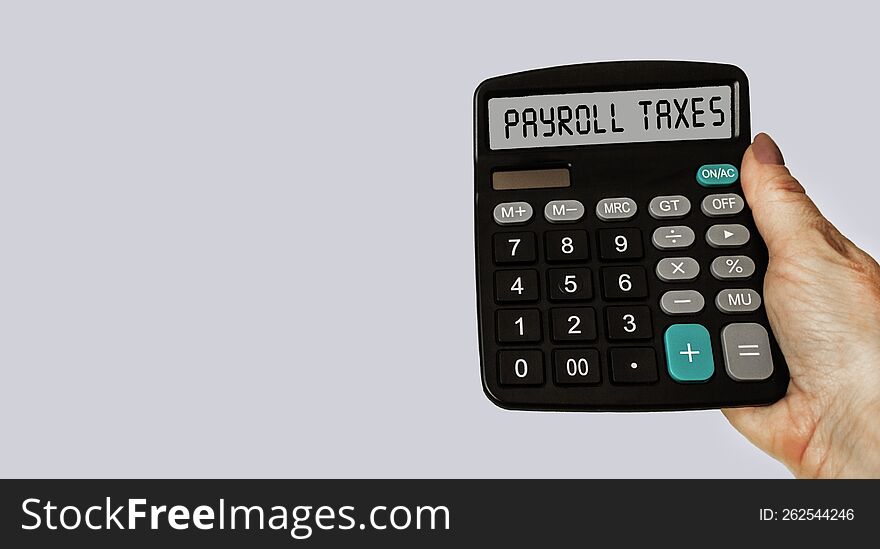 Payroll taxes concept on calculator display. A woman& x27 s hand is holding a calculator. The concept of taxes on business and wa