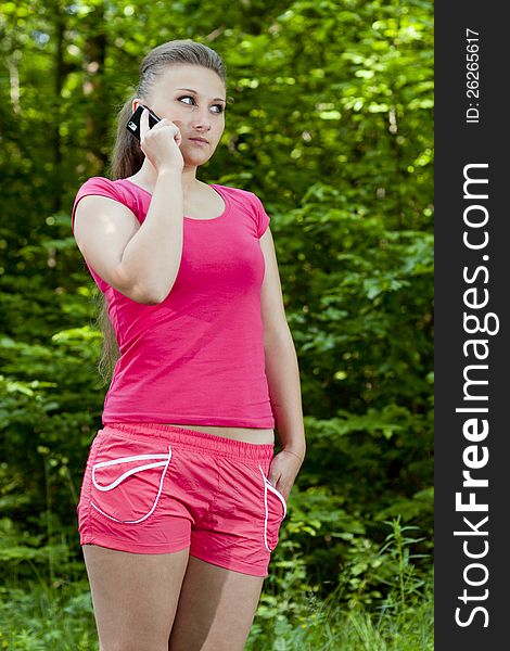 Young woman with mobile phone on the background of the park