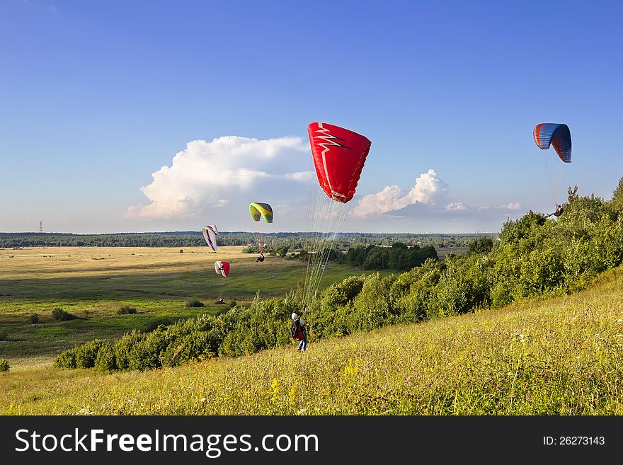 Multiple paragliders soar in the air amid wondrous landscape