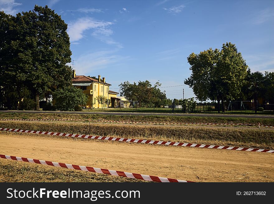 Parking On A Dirt Field Next To A Country Road And Mansion At Sunset In Summer