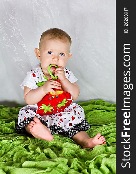 Baby girl in strawberry's dress with her toy rattle. Baby girl in strawberry's dress with her toy rattle