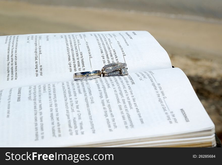 Just some wedding rings on a bible on a beach by the ocean