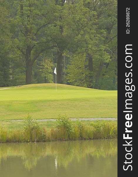 Flag and the green golf field reflecting in the water