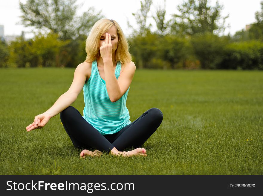 Blond woman on green grass doing yoga meditation. Blond woman on green grass doing yoga meditation