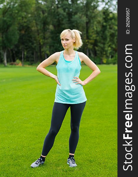 Young woman doing fitness as she is standing in the grass. Young woman doing fitness as she is standing in the grass