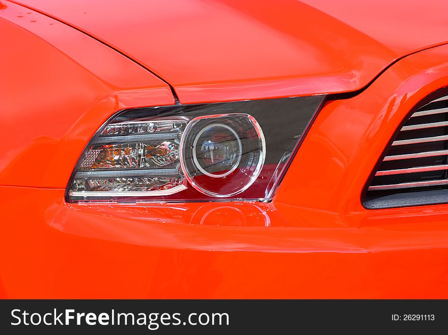 Head-light of a new, red, sport`s vehicle, closeup shot