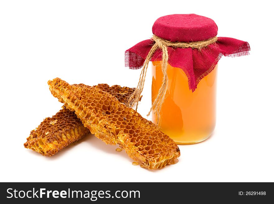 A jar of honey with honeycombs on a white background
