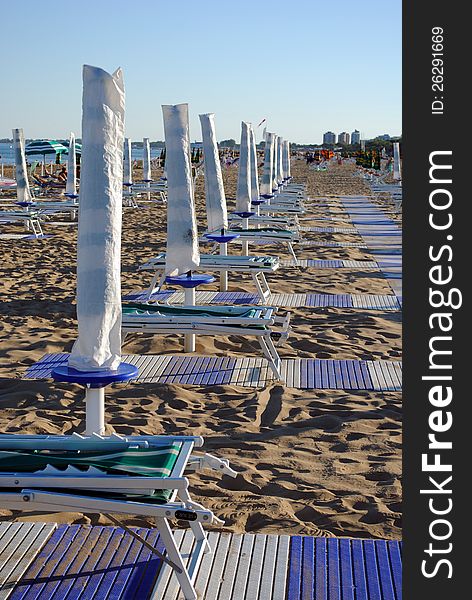 Beach umbrellas and sunbed over sand at the sunset