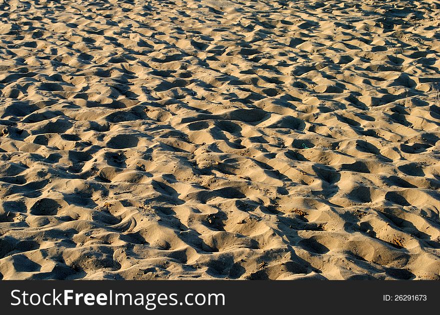 Sandy beach with sunset lights and shadows, as background