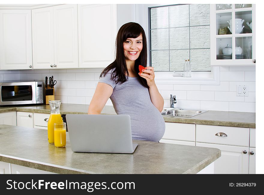 Pregnant lady with strawberry in kitchen