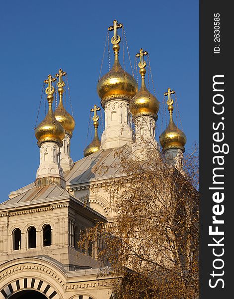 Gold cupolas, crosses and white walls of orthodox church in clear blue sky. Geneva, Switzerland. Gold cupolas, crosses and white walls of orthodox church in clear blue sky. Geneva, Switzerland.