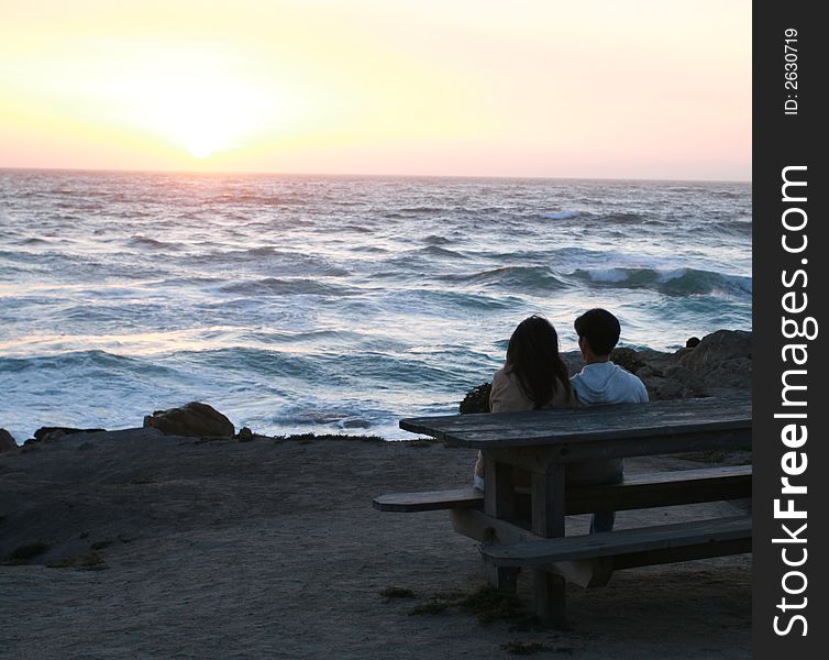 Couple watching the sun set over the Pacific Ocean. Couple watching the sun set over the Pacific Ocean