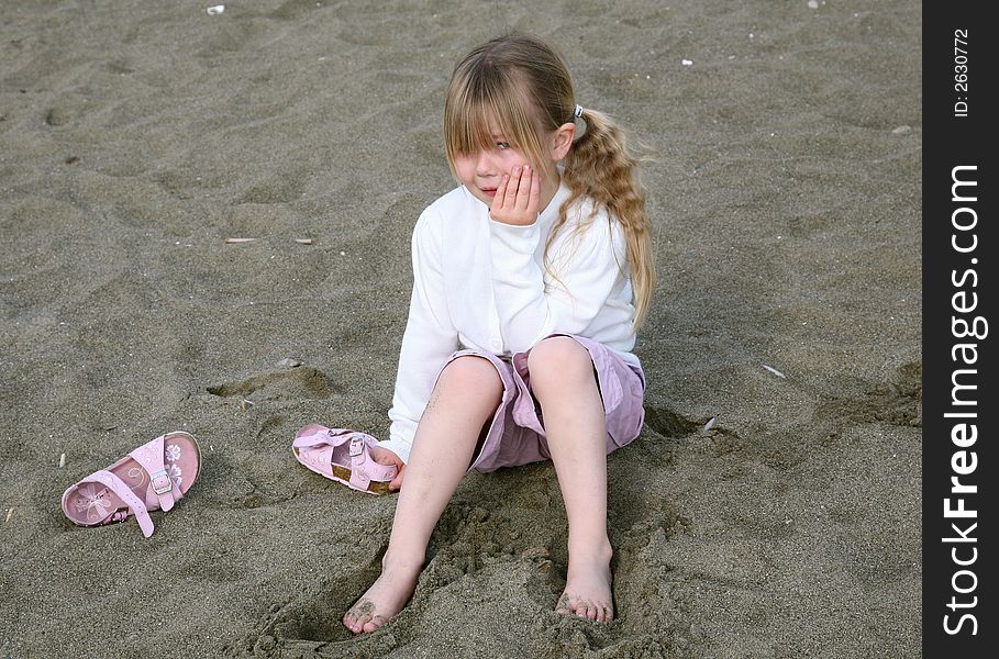 A young girl having a tantrum sat on a beach. A young girl having a tantrum sat on a beach