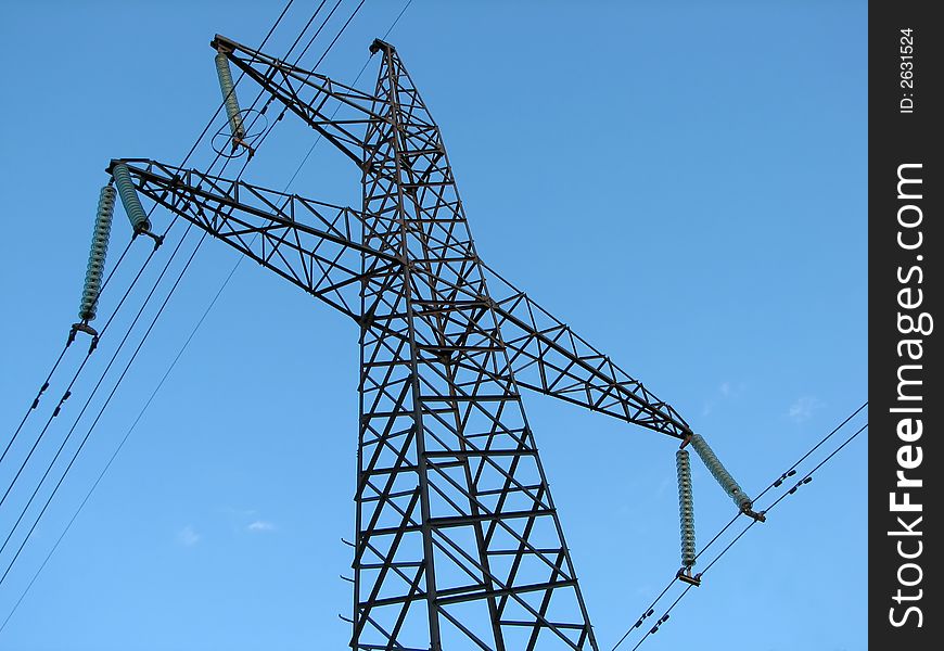 Powerline tower seen from below against blue sky