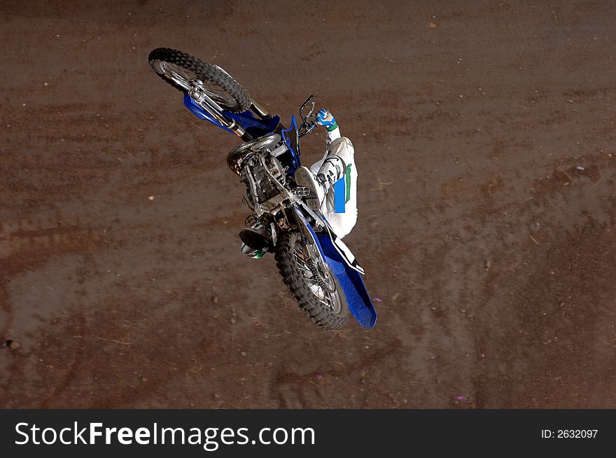 A freestyle moto-x rider goes through a trick during an indoor competition.