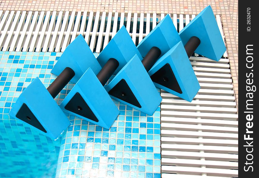 Four blue aqua dumbbells lie on the coast swimming-pool