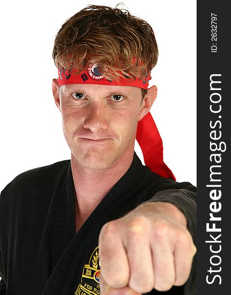 Attractive 30 something man in martial arts uniform punching towards camera.