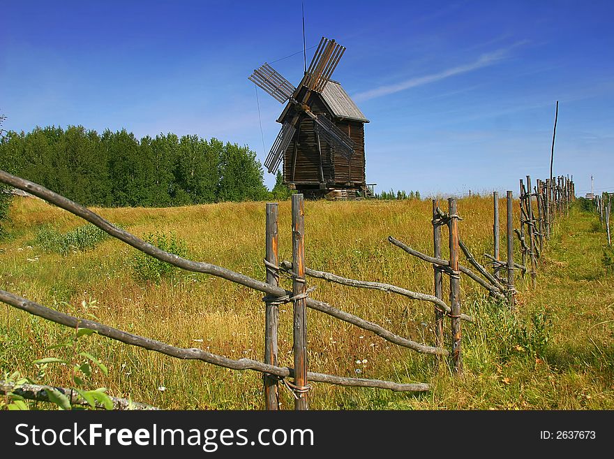 Old wooden windmill in the forest under the sky with clouds. Old wooden windmill in the forest under the sky with clouds