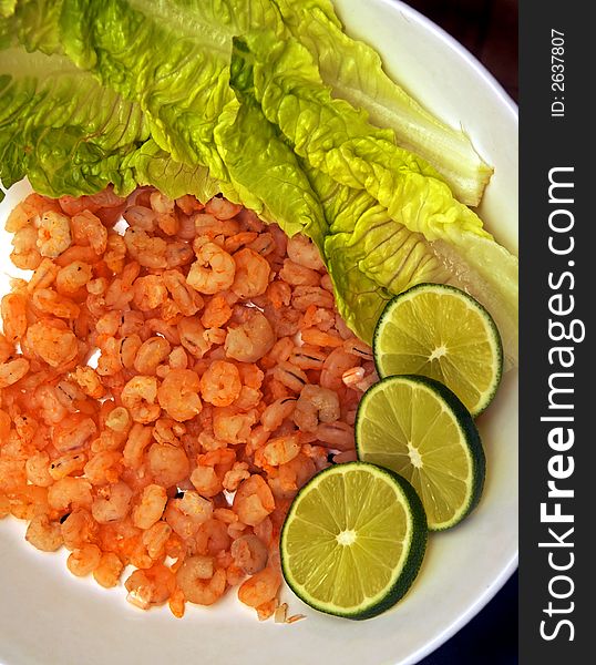 Shrimps on the plate with the limes and salad