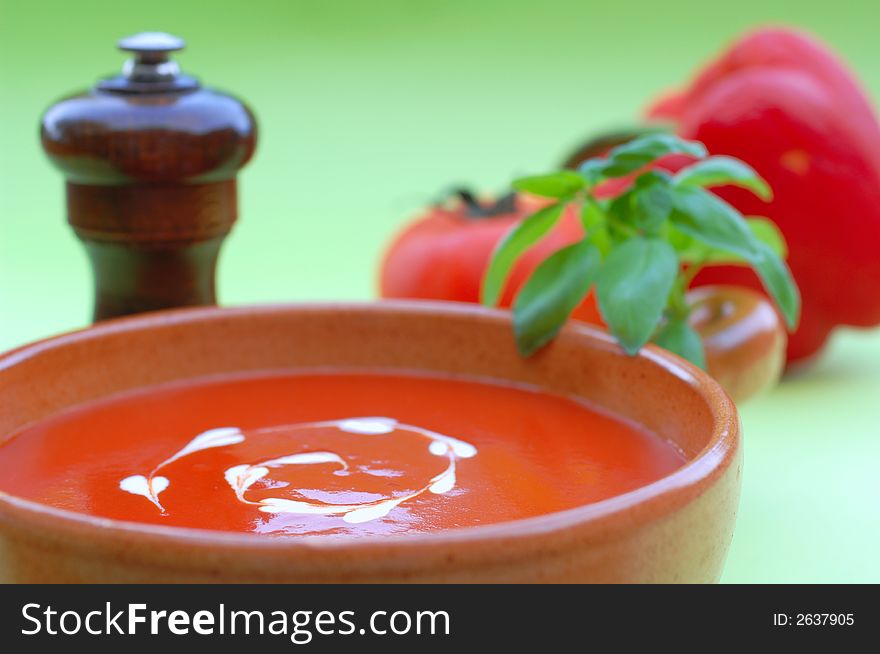 Fresh healhty tomato soup garnished with heart shaped cream drops and basil