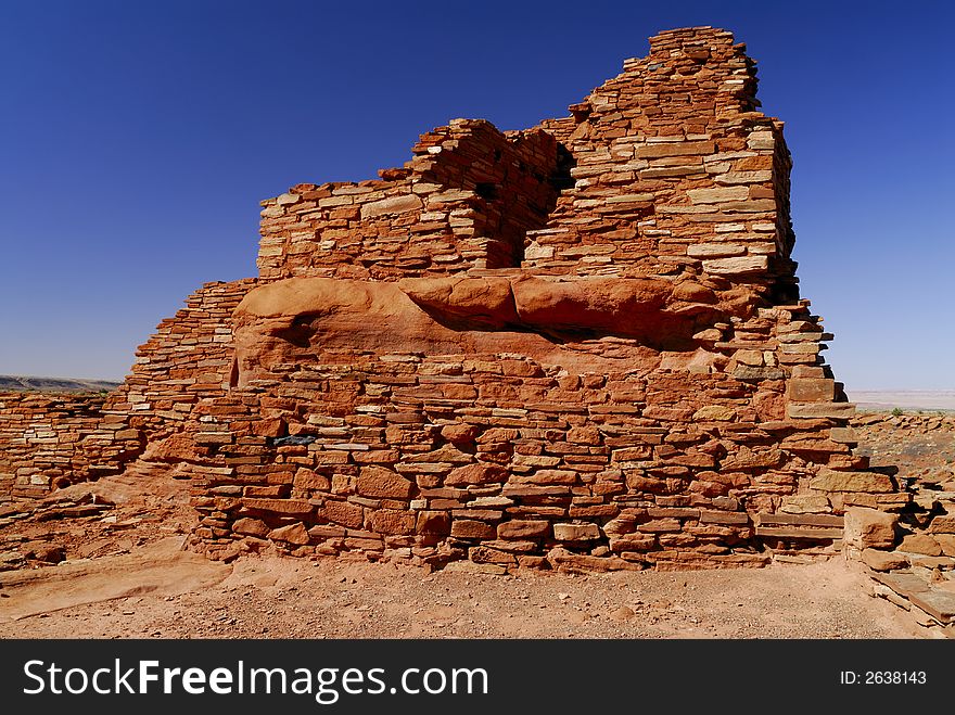 The red masonary walls of the Lomaki indian pueblo ruins against a blue Arizona sky in Wupatki National Monument. The red masonary walls of the Lomaki indian pueblo ruins against a blue Arizona sky in Wupatki National Monument