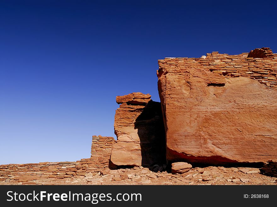 The red masonary walls of indian pueblo ruins against a blue Arizona sky in Wupatki National Monument. The red masonary walls of indian pueblo ruins against a blue Arizona sky in Wupatki National Monument