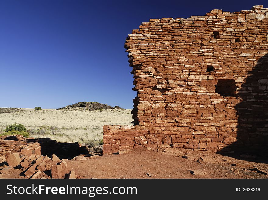 The red masonary walls of the Lomaki indian pueblo ruins against a blue Arizona sky in Wupatki National Monument. The red masonary walls of the Lomaki indian pueblo ruins against a blue Arizona sky in Wupatki National Monument